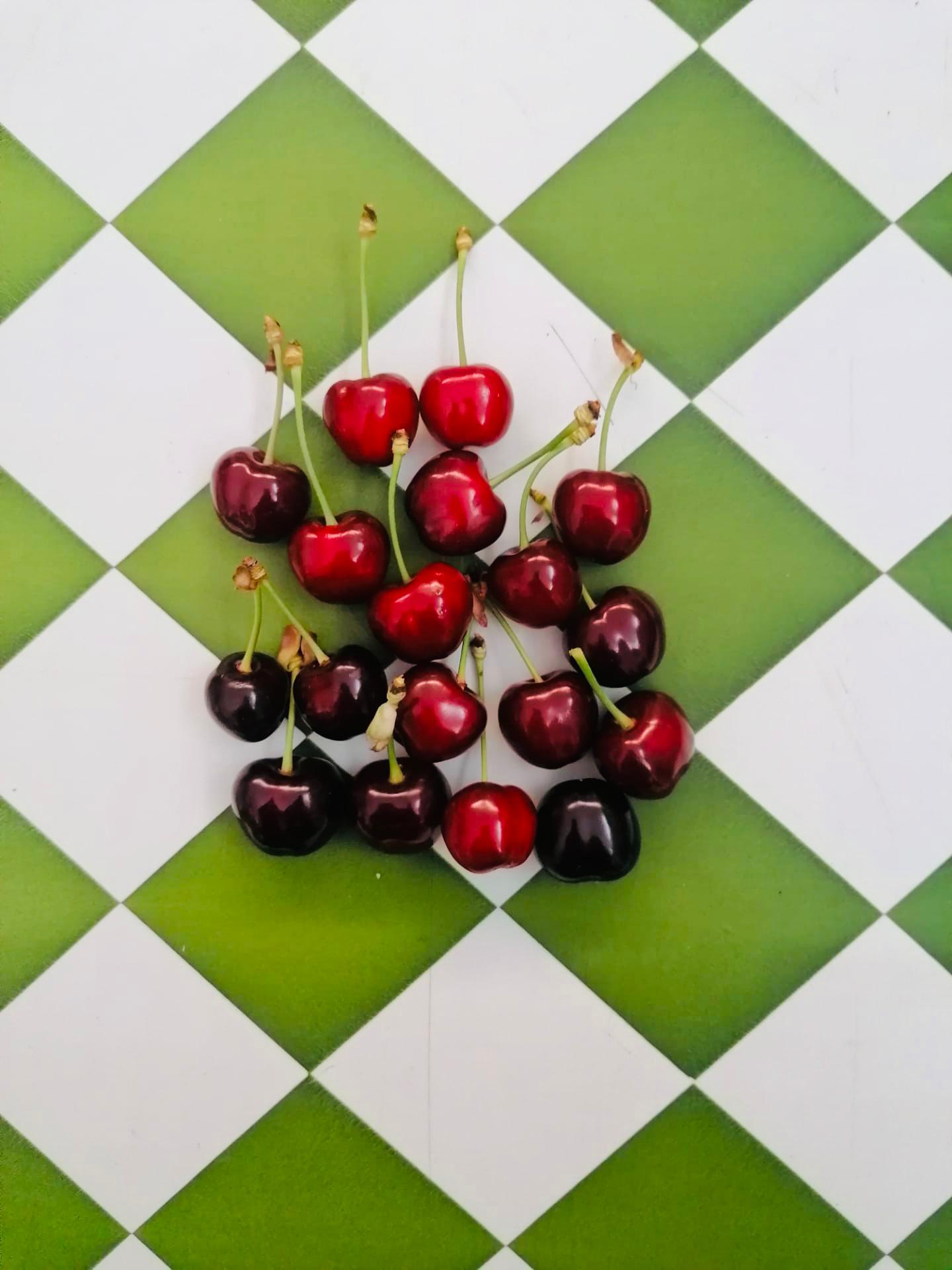 Cereja Cerejas vermelhas sobre tabuleiro de cerâmica verde e branco