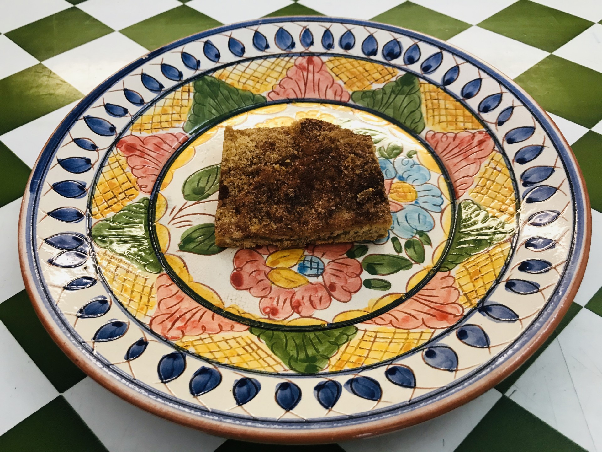 Boleimas da Ti Susana Prato cerâmico decorado com pedaço de alimento sobre azulejos brancos e verdes