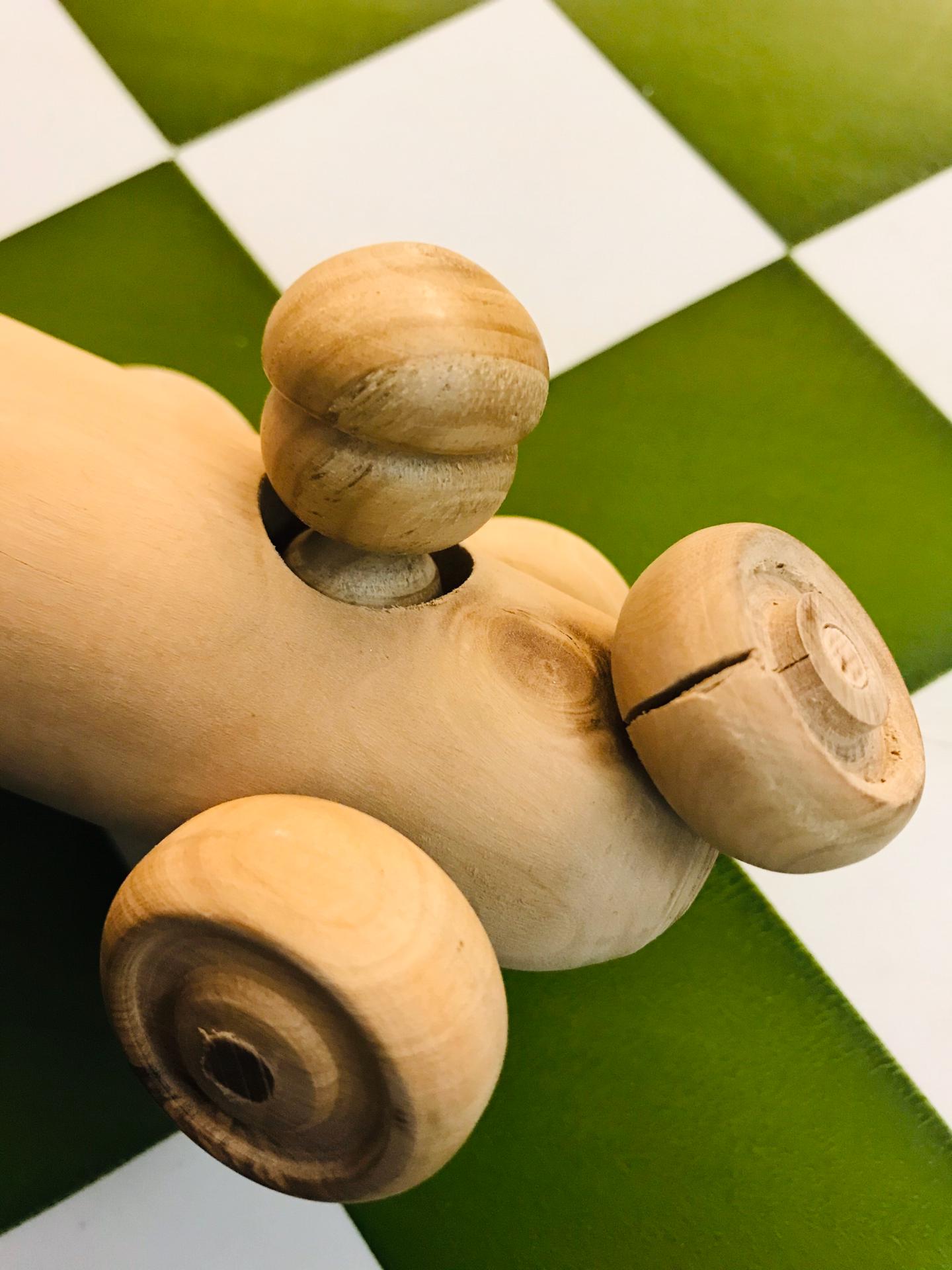 Carrinho de madeira oliveira Brinquedo de madeira com rodas sobre piso quadriculado verde e branco