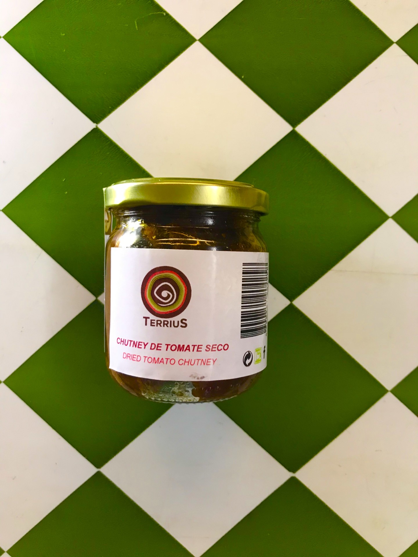 Chutney Tomate seco 190 gr Ter Frasco de chutney de tomate seco Terrius com tampa dourada sobre azulejos verdes e brancos