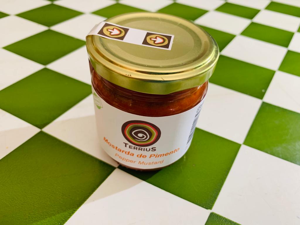 Mostarda de Pimentos Frasco de mostarda Ferrius sobre superfície de xadrez verde e branco