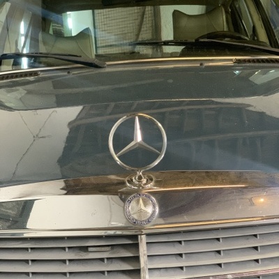 Frente de automóvel Mercedes-Benz preto com emblema metálico da marca.