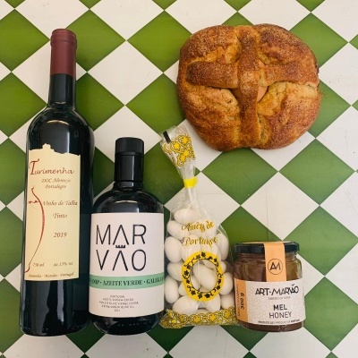 Produtos alimentares sobre fundo quadriculado verde e branco, incluindo vinho, azeite, amêndoas e mel com pão