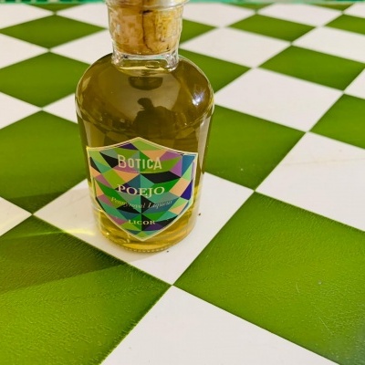 Frasco de vidro com líquido amarelo e etiqueta colorida