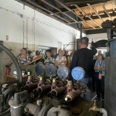 Interior de fábrica antiga com maquinaria e turistas em visita guiada