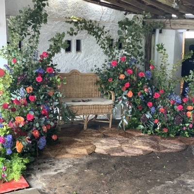 Banco de vime rodeado por flores coloridas sob varanda