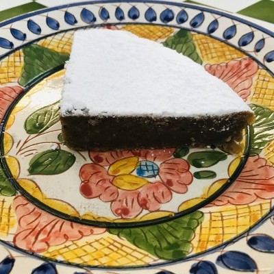 Fatia de bolo com açúcar em pó num prato cerâmico decorado com flores e folhas coloridas