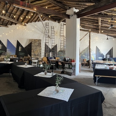 Interior de espaço rústico com mesas negras e iluminação suave