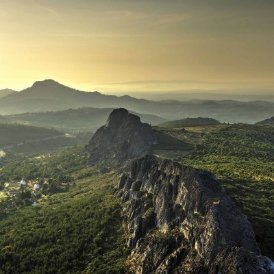 Paisagem montanhosa com vegetação e formação rochosa ao pôr do sol