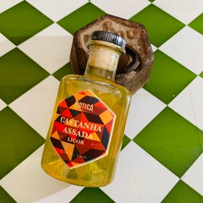 Garrafa de licor Botica Castanha Assada sobre azulejos brancos e verdes
