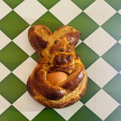 Pão em forma de coelho com ovo em fundo quadriculado verde e branco