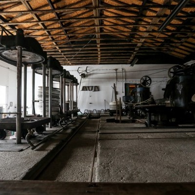 Interior de fábrica antiga com máquinas industriais de metal e estrutura de telhado em madeira