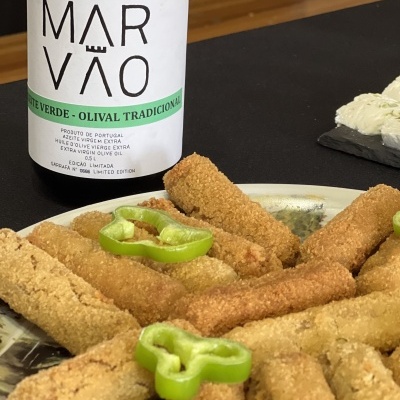 Garrafa de azeite verde Marvão com palitos crocantes e pimento verde num prato.