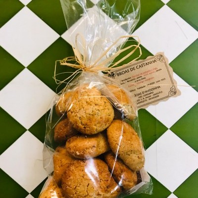 Pacote de broas de castanha em plástico transparente com etiqueta e fundo xadrez verde e branco