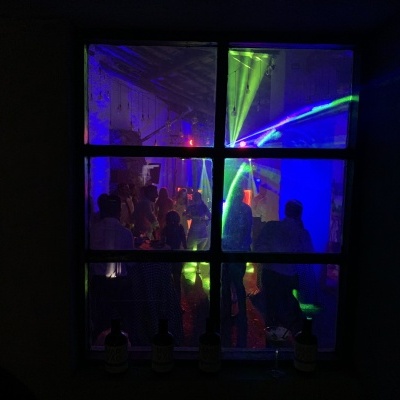 Janela com festa iluminada por luzes coloridas e garrafas no parapeito