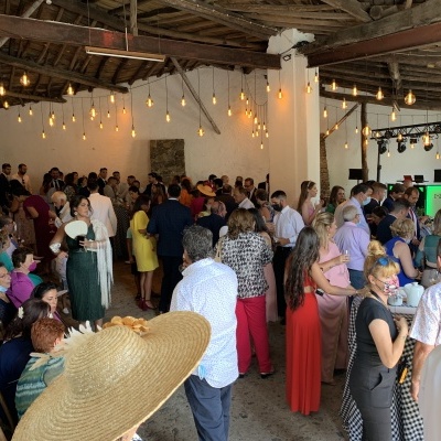 Multidão em espaço rústico com teto de madeira e lâmpadas penduradas