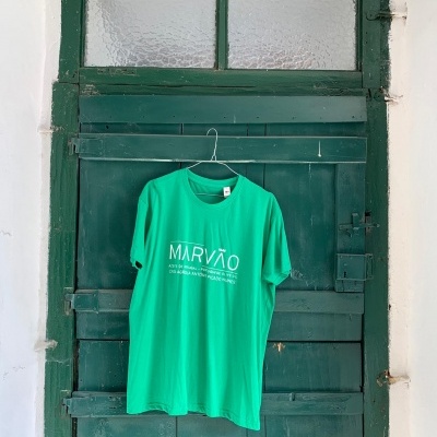 T-shirt verde pendurada numa porta verde escura