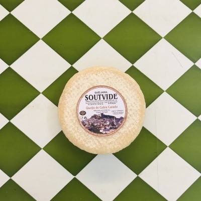 Queijo redondo com etiqueta na mesa de azulejos verde e branco