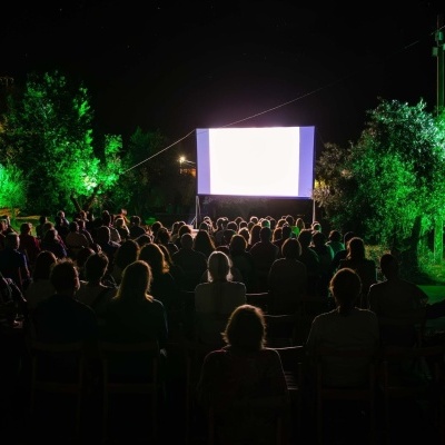 Cinema ao ar livre à noite com ecrã e público sentado