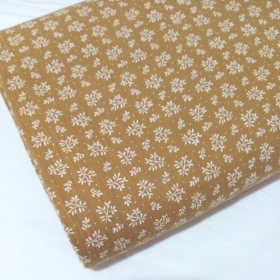 Musselina com raminhos brancos em fundo caramelo