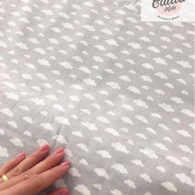 Tecido cinza claro com padrão de nuvens brancas e mão tocando o tecido