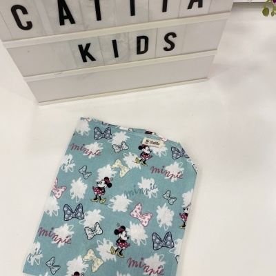 Pano azul claro com estampado de Minnie Mouse e laços, em superfície branca com caixa de luz com texto 'CATITA KIDS' e flor roxa