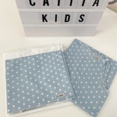 Cobertor e pijama azul claro com estrelas brancas ao lado de caixa luminosa com texto CATITA KIDS