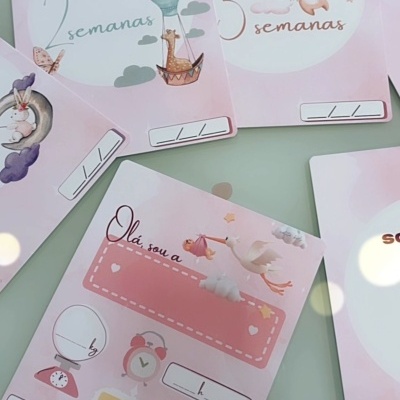 Cartões comemorativos para bebês com semanas e calendário em tons de rosa e ilustrações infantis.