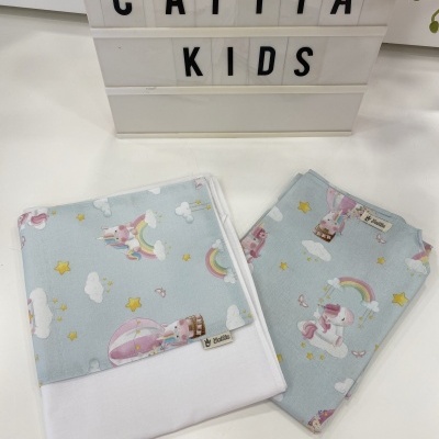 Artigos têxteis infantis azuis com estampados de arco-íris e estrelas.