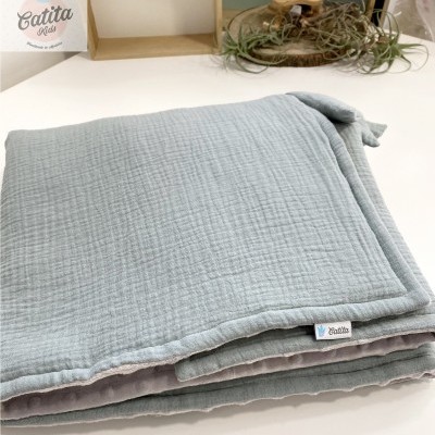 Manta cinzenta clara dobrada com etiqueta Catita Kids