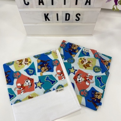 Lençol e fronha para cama infantil com padrão colorido de cães e ossos, etiqueta I Kiddo, caixa CATITA KIDS ao fundo