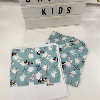 Toalha e babete com padrão Minnie Mouse em azul claro sobre mesa branca