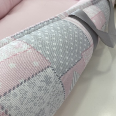 Ninho para bebé com tecido em padrão de retalhos cinza, rosa e branco com fita cinzenta