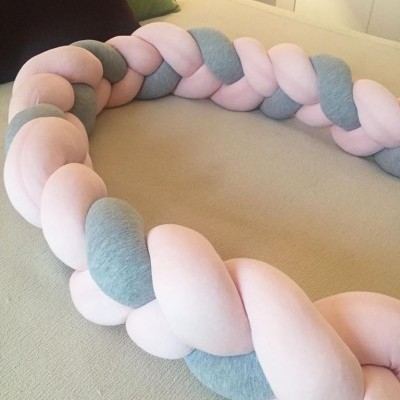 Trança decorativa em tecido rosa claro e cinza sobre superfície bege