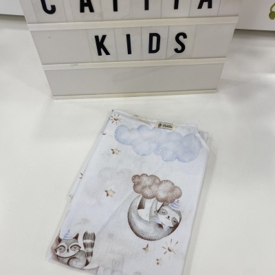 Toalha infantil branca com estampado de nuvens e animais, à frente de placa com texto 'CATITA KIDS'.