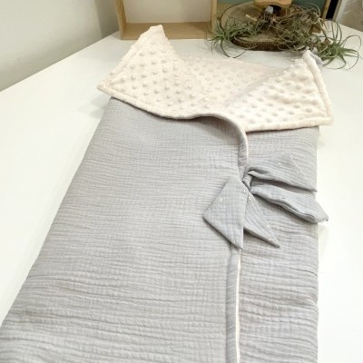 Sacola infantil cinza claro com interior branco texturizado em mesa branca com decoração em madeira