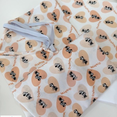 Tecido com padrão de corações rosas e bege com Minnie Mouse em preto e branco e texto minnie, com elástico branco