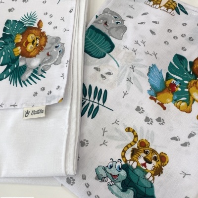 Toalhas infantis brancas com desenhos de animais e folhas verdes.