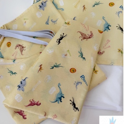 Tecidos amarelos com estampado de dinossauros e elásticos brancos.