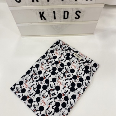 Lenço estampado com rostos do Mickey Mouse sobre superfície branca e caixa de luz com texto