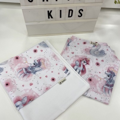 Tecidos infantis com estampas de unicórnios e cisnes em cores rosa, branco e cinza, próximo a letreiro com 'CATITA KIDS'.