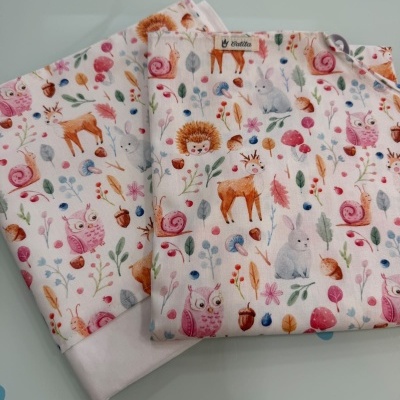 Tecidos dobrados com padrão colorido de animais e plantas em fundo branco e etiqueta Catita