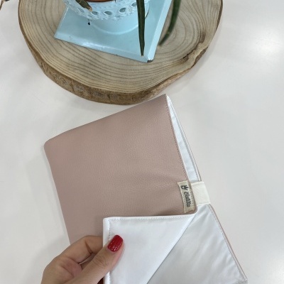 Capa bege claro com interior branco e etiqueta Catita Kids junto a planta em vaso azul sobre base de madeira