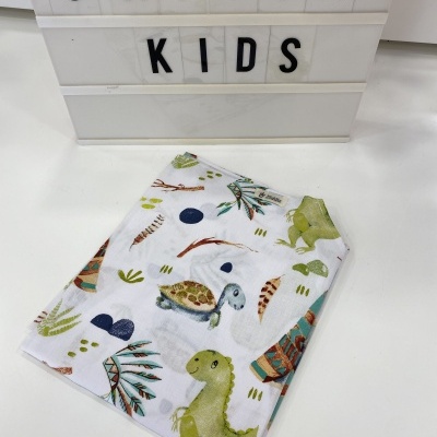 Lençol infantil branco com padrão de dinossauros coloridos sobre superfície branca