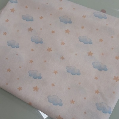 tecido branco com nuvens azuis e estrelas cor de bege dobrado