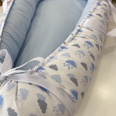 Ninho para bebé azul e branco com padrão de nuvens e fitas