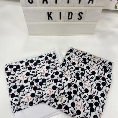 Tecidos com padrão Mickey Mouse em preto, branco e vermelho, caixa de luz com texto 'CATITA KIDS' e orquídea lilás.