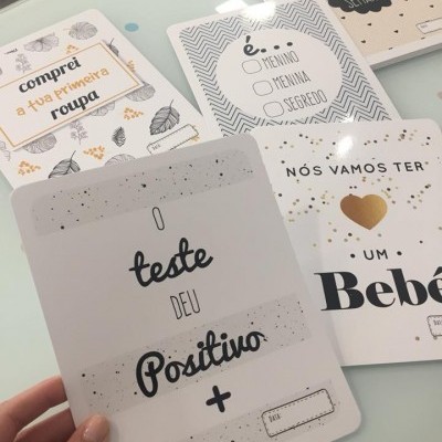 Cartões com mensagens de anúncio de gravidez em português, sobre superfície clara.