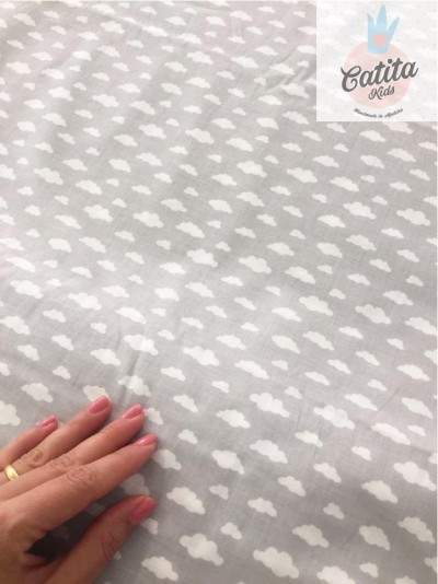 Tecido cinza claro com padrão de nuvens brancas e mão tocando o tecido