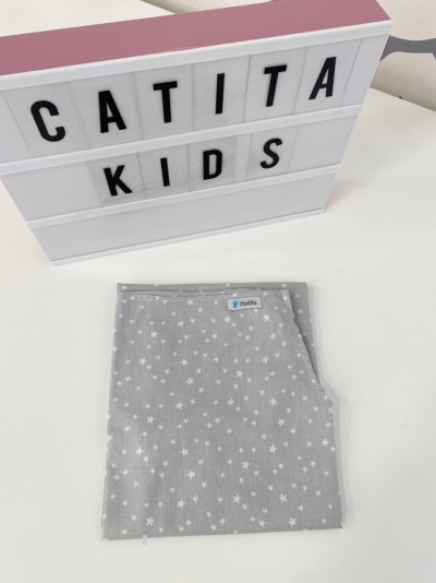 Lençol cinzento para crianças com estrelas brancas dobrado sobre superfície branca com caixa de luz 'CATITA KIDS'